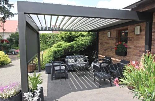 Offenes Lamellendach mit Seitenmarkise über einer Sitzgruppe einer Terrasse